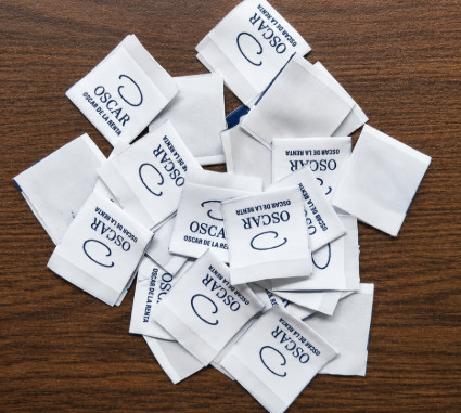 White woven brand labels with the blue OSCAR DE LA RENTA logo